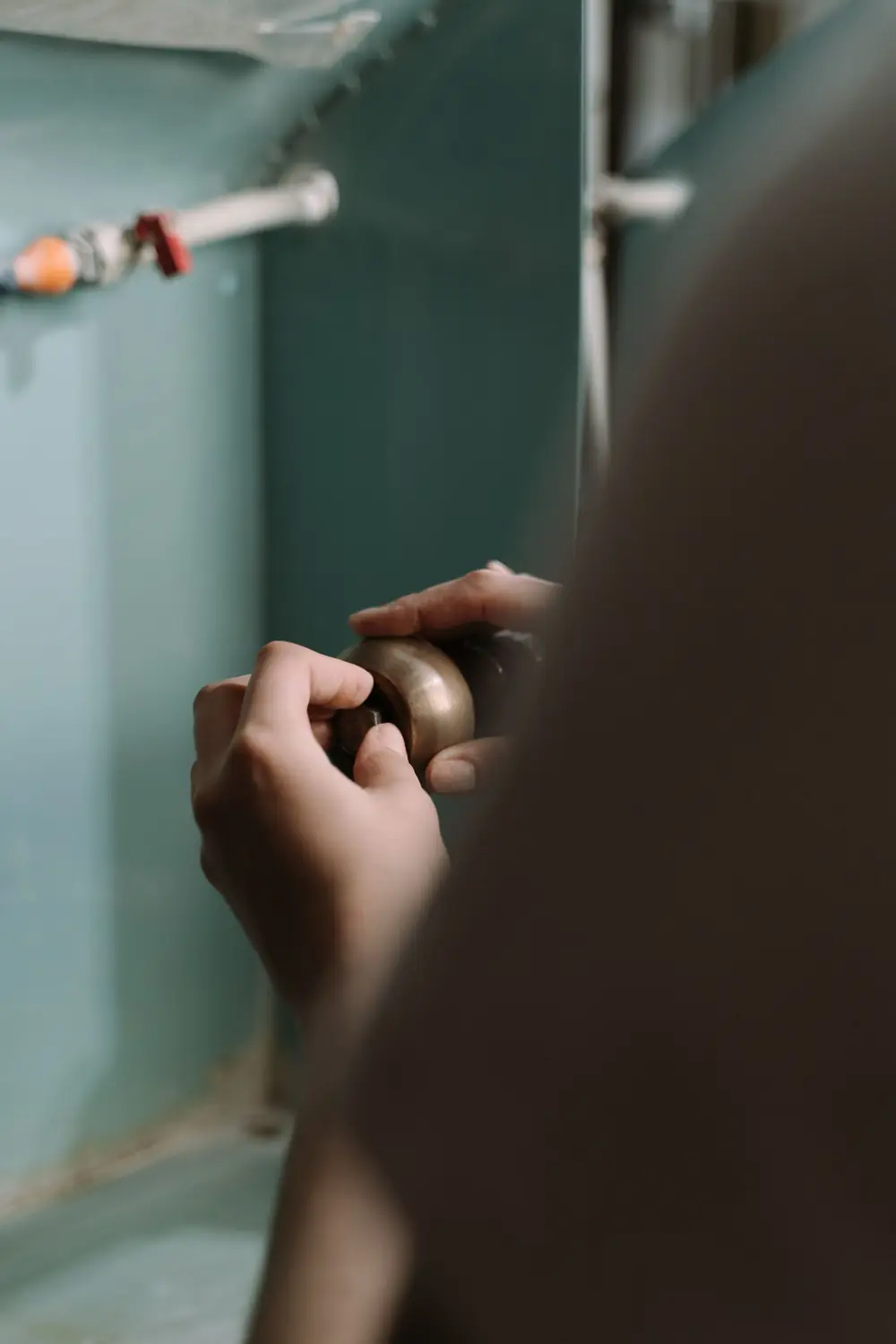 Hands adjusting a brass plumbing valve on a home water line
